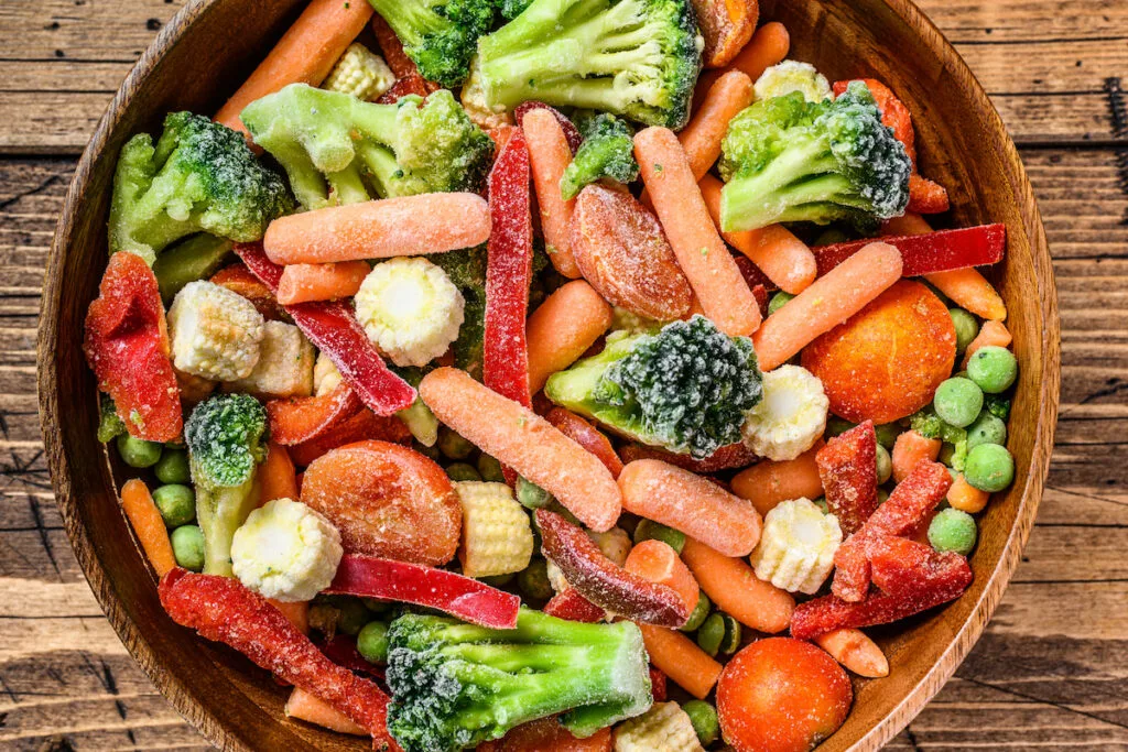 Frozen cut vegetables corn carrot watermelon broccoli in wooden bowl 