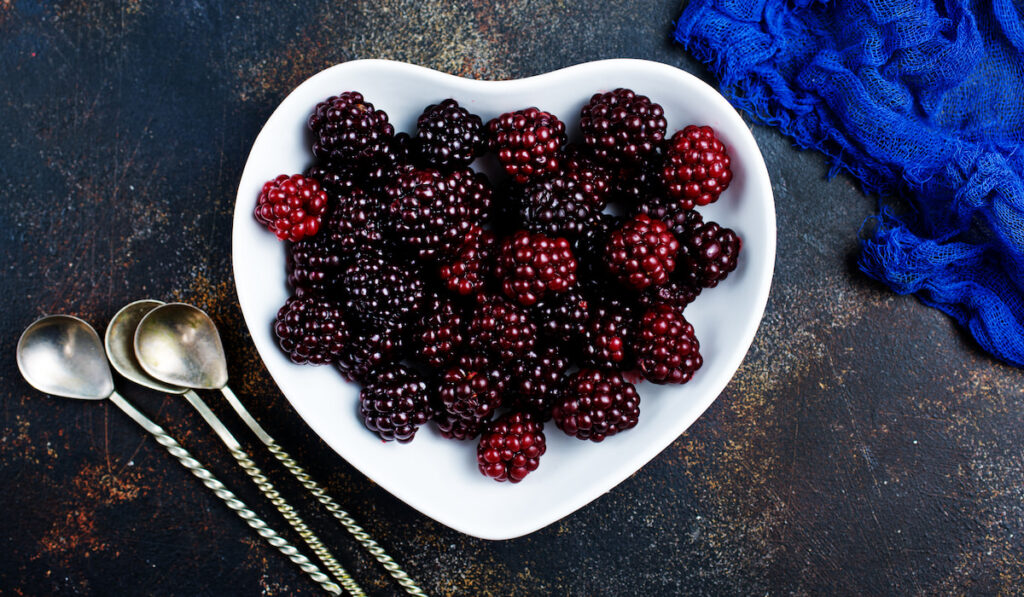 fresh blackberries on heart shape plate and small teaspoons