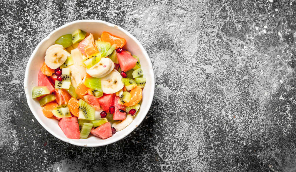 mix of sliced fruits in white bowl on black background