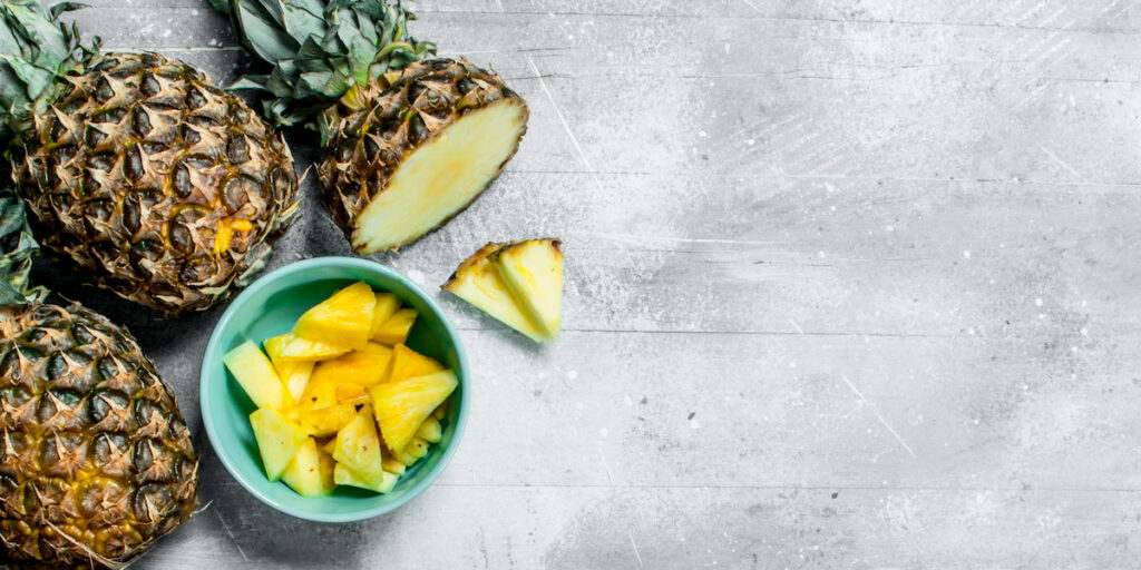 pieces of fresh sliced pineapples in a bowl and ripe pineapples