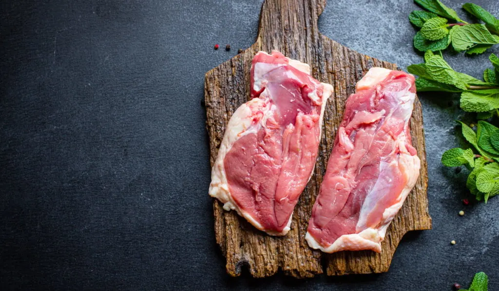 raw meat on wooden board with mint leaves 