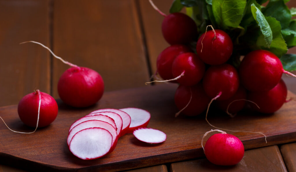 ripe sliced and whole red radish with leaves 