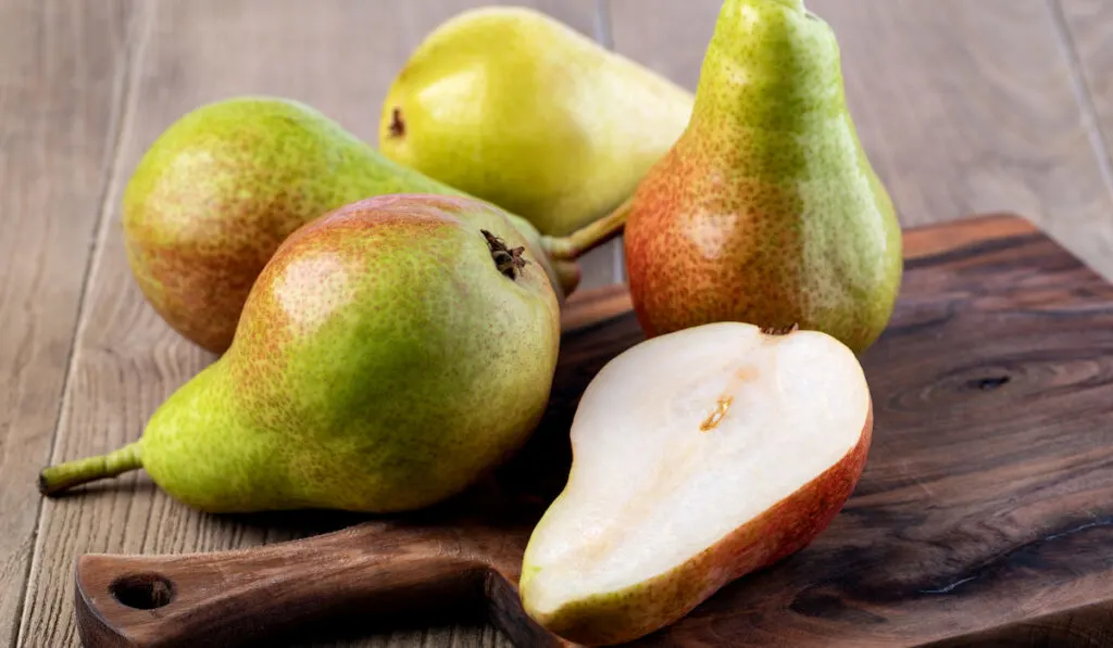 whole and sliced pears on wooden board 