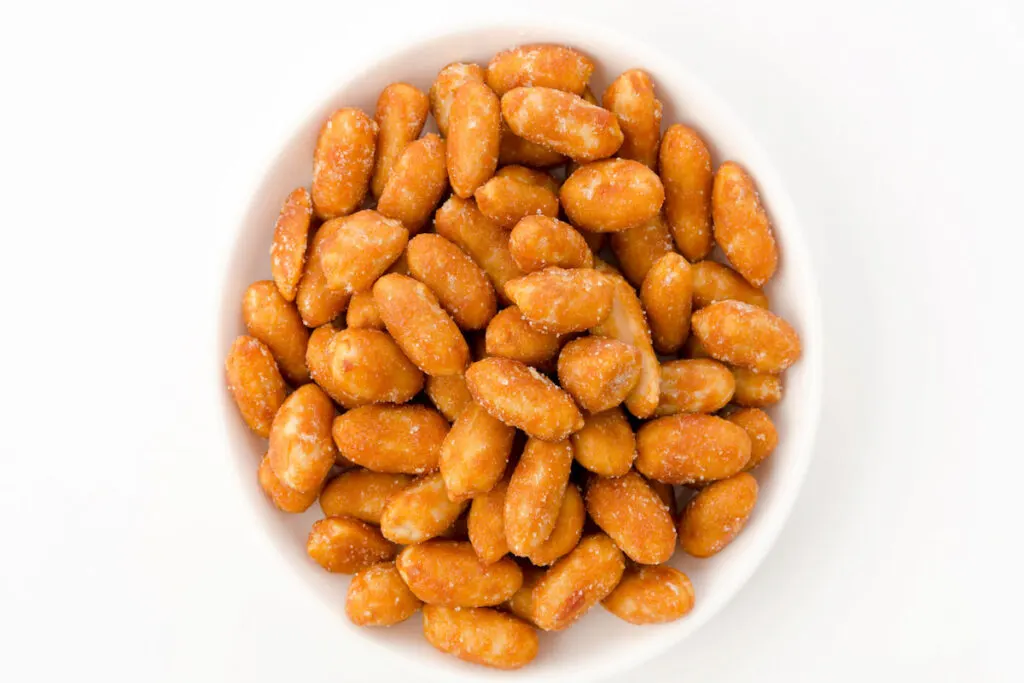 Honey roasted peanuts in white bowl on white background