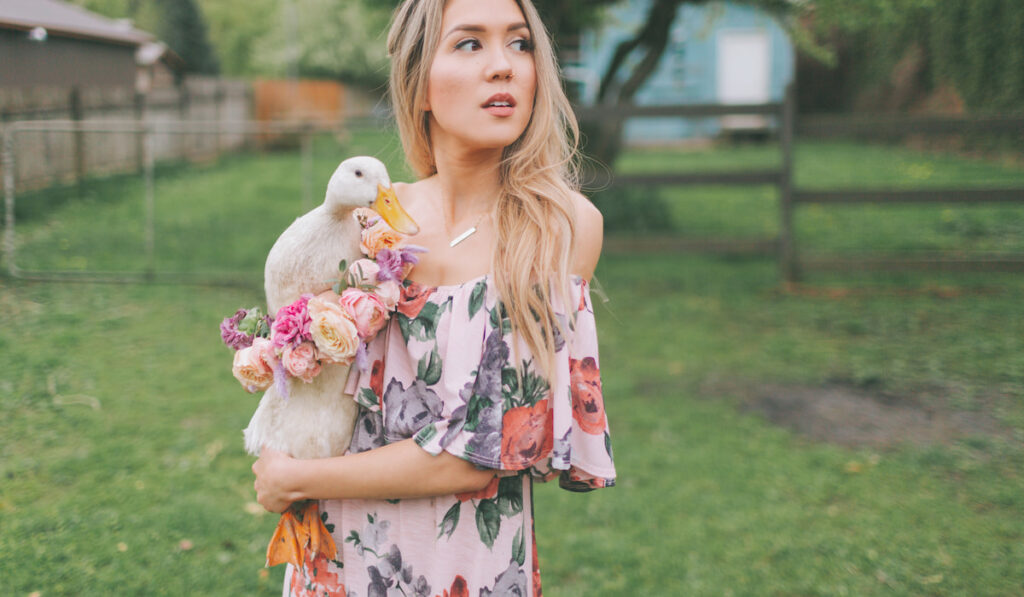 A woman holding a duck with flowers posing outdoor