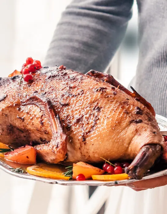 Christmas-roast-duck-with-apples-and-oranges-in-female-hands