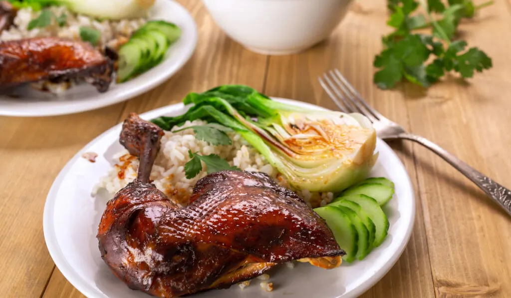 Soy Sauce Honey Glaze Duck with bok choi and rice on a white plate