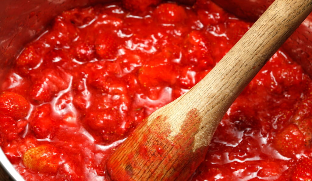 mashed strawberries and a wooden spoon