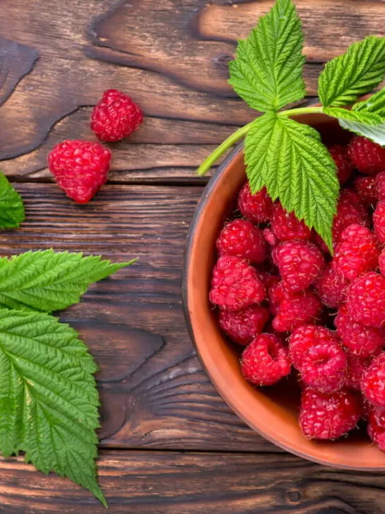 raspberries on top of a table with mint leaves at the sides