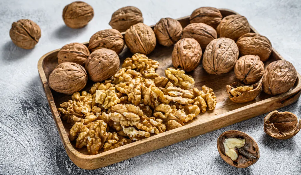 Walnuts in a wooden plate and walnut kernels