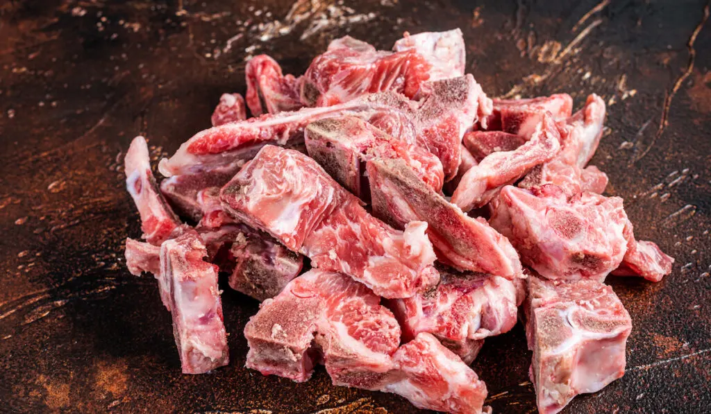 Raw meat on the bone diced for stew on dark background