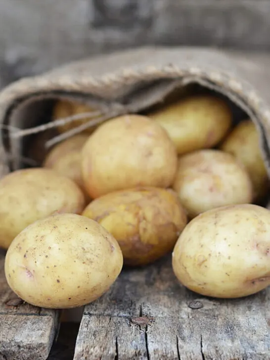 Sack fresh organic potatoes on a wooden table - ss230909